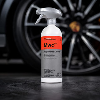 A bottle of MWC Magic Wheel Cleaner by Red Dragon is shown in sharp focus in the foreground, with a blurred car wheel in the background on a dark surface.