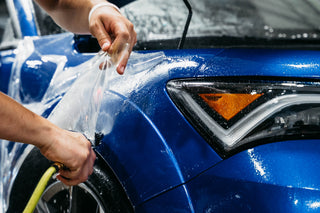 Person applying car wrap to a blue car